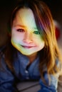 Rainbow reflection on the face of a little girl smiling and looking at the camera