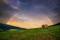 Rainbow rural landscape with field and bale of hay. Typical hill near slovak village at summer time, Slovakia.