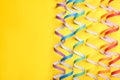 Rainbow serpentine streamers on yellow background, flat lay with space for text. LGBT pride