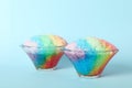 Rainbow shaving ice in glass dessert bowls on light blue background Royalty Free Stock Photo