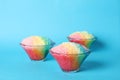 Rainbow shaving ice in glass dessert bowls on light blue background Royalty Free Stock Photo