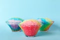 Rainbow shaving ice in glass dessert bowls on blue background Royalty Free Stock Photo
