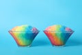 Rainbow shaving ice in glass dessert bowls on light blue background Royalty Free Stock Photo