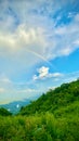 Rainbow sky and mountain. Springtime landscape grassy field rolling hills. Royalty Free Stock Photo