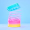 Rainbow slinky toy, spring and plastic product in studio isolated against a blue background mockup. Flexible toys