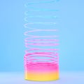 Rainbow slinky toy, spring and plastic product in studio isolated against a blue background mockup. Flexible toys Royalty Free Stock Photo