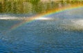 Rainbow spray fountain on the background of the river Royalty Free Stock Photo