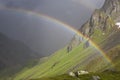 Rainbow stretching over a mountain valley in front of dark thunder storm- Royalty Free Stock Photo