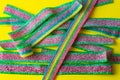 Rainbow stripes of sweets made of sour jelly in sugar sprinkles on a yellow background. Top view. Royalty Free Stock Photo