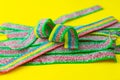 Rainbow stripes of sweets made of sour jelly in sugar sprinkles on a yellow background. Top view. Royalty Free Stock Photo