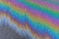 rainbow stripes on wet asphalt after fuel spill from car. Royalty Free Stock Photo