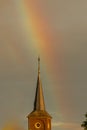 A rainbow touching religious cross on top of a catholic church in Itteren near Maastricht Royalty Free Stock Photo