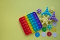 A rainbow toy and puzzles lie on a yellow background. Blue and Orange Funny Interactive Anti-Stress Silicone Toys. Pop