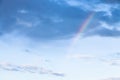 Rainbow under rainy clouds in blue evening sky Royalty Free Stock Photo