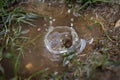 Raindrop falling into a small puddle and creating a small water dome