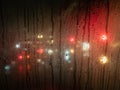 Raindrops on a bus window with blurred headlights behind