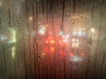 Raindrops on a bus window with blurred headlights behind