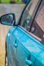 Raindrops on the car. Car element with raindrops close-up. Doors, mirror and glass of a blue car in raindrops. Big raindrops on Royalty Free Stock Photo