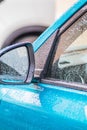 Raindrops on the car. Car element with raindrops close-up. Doors, mirror and glass of a blue car in raindrops. Big raindrops on Royalty Free Stock Photo