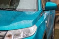 Raindrops on the car. Car element with raindrops close-up. The hood, mirror and glass of a blue car covered in raindrops. Big