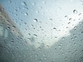 Raindrops on car's glass with blurry cloudy sky and village. Royalty Free Stock Photo