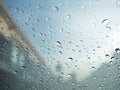 Raindrops on car's glass with blurry cloudy sky and village. Royalty Free Stock Photo