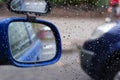 Raindrops on car side view mirror and window closeup. Bad weather driving Royalty Free Stock Photo