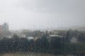 Raindrops cascading over a window during a stormy afternoon in a city Royalty Free Stock Photo