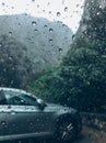 Raindrops on the clean car glass image with silver color car on the background. Deep autumn cold rainy foggy day photo on the Royalty Free Stock Photo