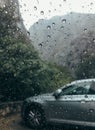 Raindrops on the clean car glass image with silver color car on the background. Deep autumn cold rainy foggy day photo on the