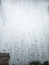 Raindrops cling to a windowpane, creating intricate patterns and distorting the muted view beyond. Royalty Free Stock Photo