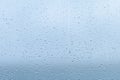 Raindrops forming a delicate pattern on a window pane, blurring the outside view during a cloudy afternoon in early fall