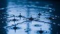 Raindrops creating ripples on a dark blue wet surface with reflections Royalty Free Stock Photo