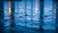 Raindrops creating ripples on a wet reflective surface with bokeh lights Royalty Free Stock Photo