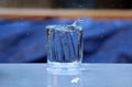 Raindrops fall into a glass of water that stands on the table in the garden Royalty Free Stock Photo