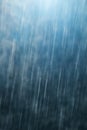 Raindrops falling against dark blue background, slow shutter speed