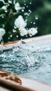 Raindrops falling into water creating a splash with blurred flowers in the background and a container edge in foreground detail. Royalty Free Stock Photo