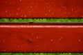 Raindrops on a painted red wooden structure. after the rain. Red bench element Royalty Free Stock Photo