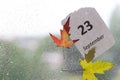 Raindrops on pane with colorful leaves and calendar sheet, calendar autumn concept Royalty Free Stock Photo