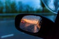 Raindrops on the rearview mirror of a car at sunset. the sunset is reflected in the car mirror Royalty Free Stock Photo