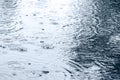 Raindrops rippling in puddle with sky reflection Royalty Free Stock Photo