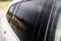 Raindrops on a silver car on the side rear black window of the car. Royalty Free Stock Photo