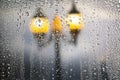 Raindrops running on window glass. Beautiful street lamps on the rain. Blurred abstract background Royalty Free Stock Photo
