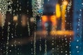 Colorful street lights on the rain. Rain drops on the window. Blurred abstract background. Royalty Free Stock Photo