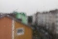 Raindrops on the window glass, on the background of blured houses and gray sky Royalty Free Stock Photo