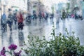 Raindrops on window glass, blurred unrecognizable people walk on road in rainy day. View from the window on city street Royalty Free Stock Photo