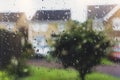 Raindrops on window glass in rainy day with blurry tree and house background, View looking trough window with water drops texture Royalty Free Stock Photo