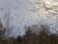 Raindrops on a window pane, on a background of heavily cloudy sky