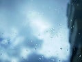 Raindrops on a window pane during a rain storm with blue grey storm clouds in the background. Royalty Free Stock Photo