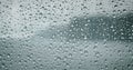 Raindrops on a window pane. Severe sea waves foam outside. Dramatic cloudy weather and rain. Calmness and pacification.